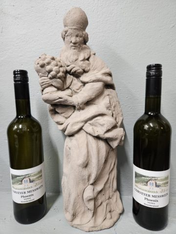 Auch zu Messwein verarbeitet Michael Rindermann Trauben vom Corveyer Hexenstieg. Die beiden Flaschen rahmen eine Statue des hl. Urban, des Schutzpatrons der Winzer. Sie ist schon lange in Michael Rindermanns Besitz.   